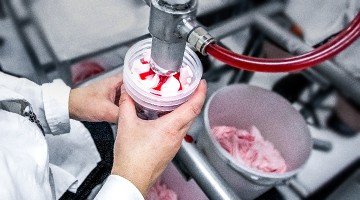 Glass jars being filled with ice cream in a manufacturer's location